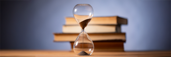 An hourglass with books in the background.